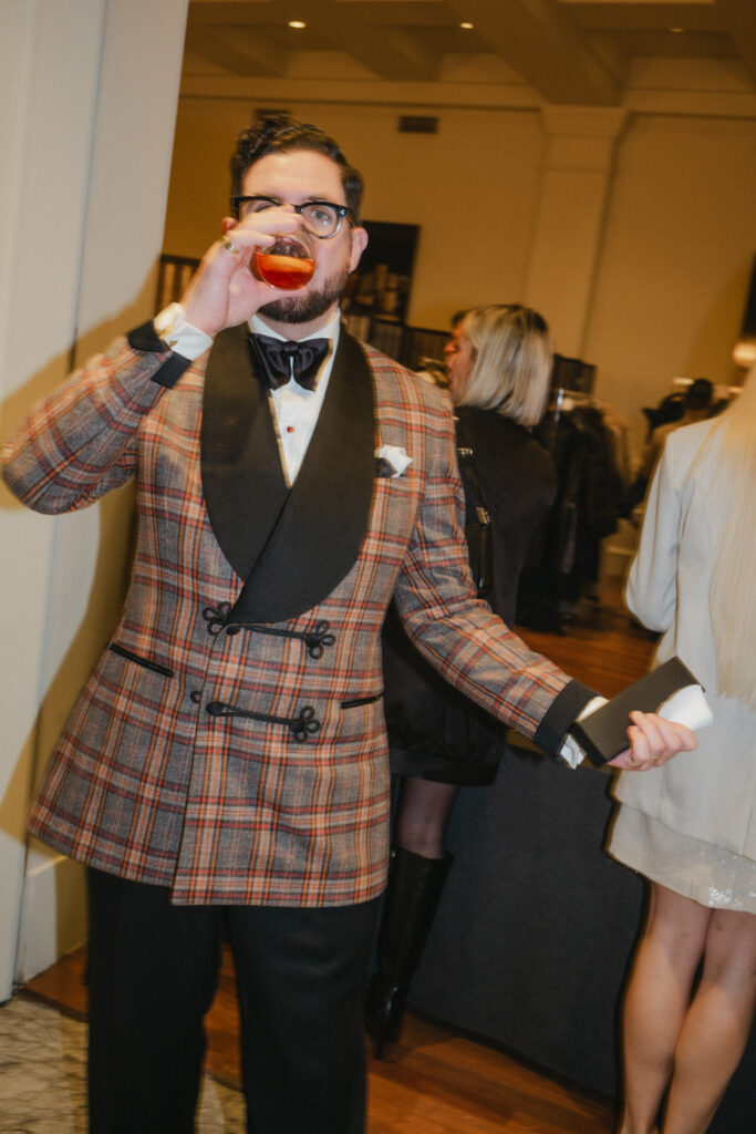 man drinking negroni wearing bow tie at a black tie event