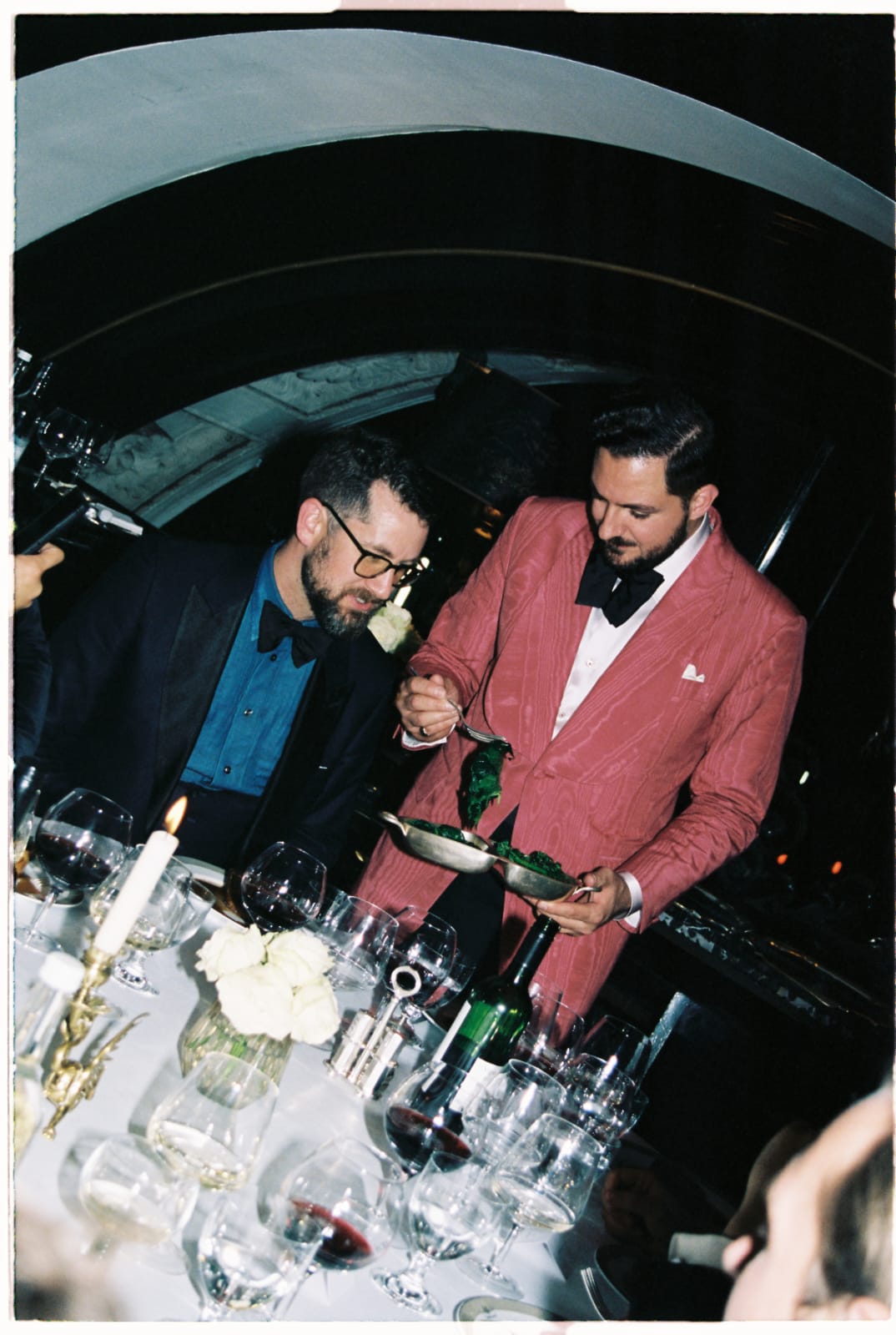 Host serves a guest at a black tie dinner party